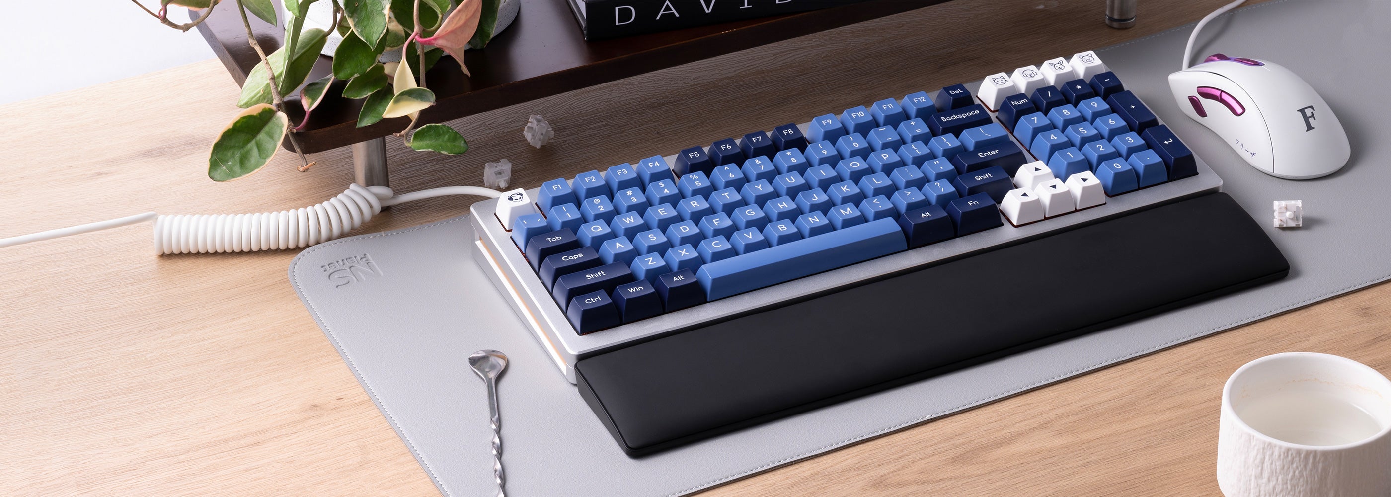 A MonsGeek wrist rest, a sleek keyboard and mouse positioned on a modern desk surface.