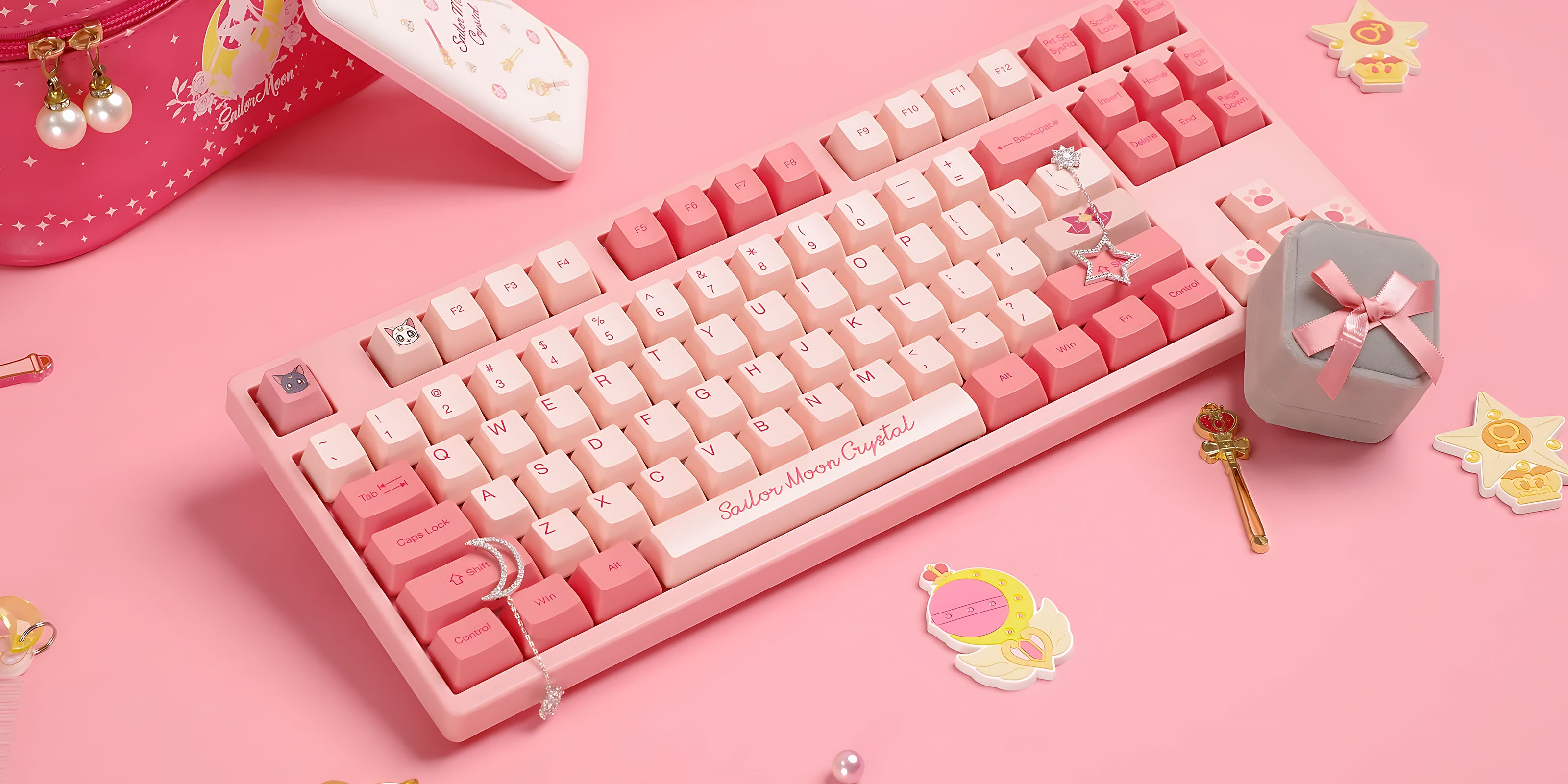 Akko Sailor Moon Crystal 3087 Keyboard surrounded by various pink Sailor Moon-themed accessories on a clean surface